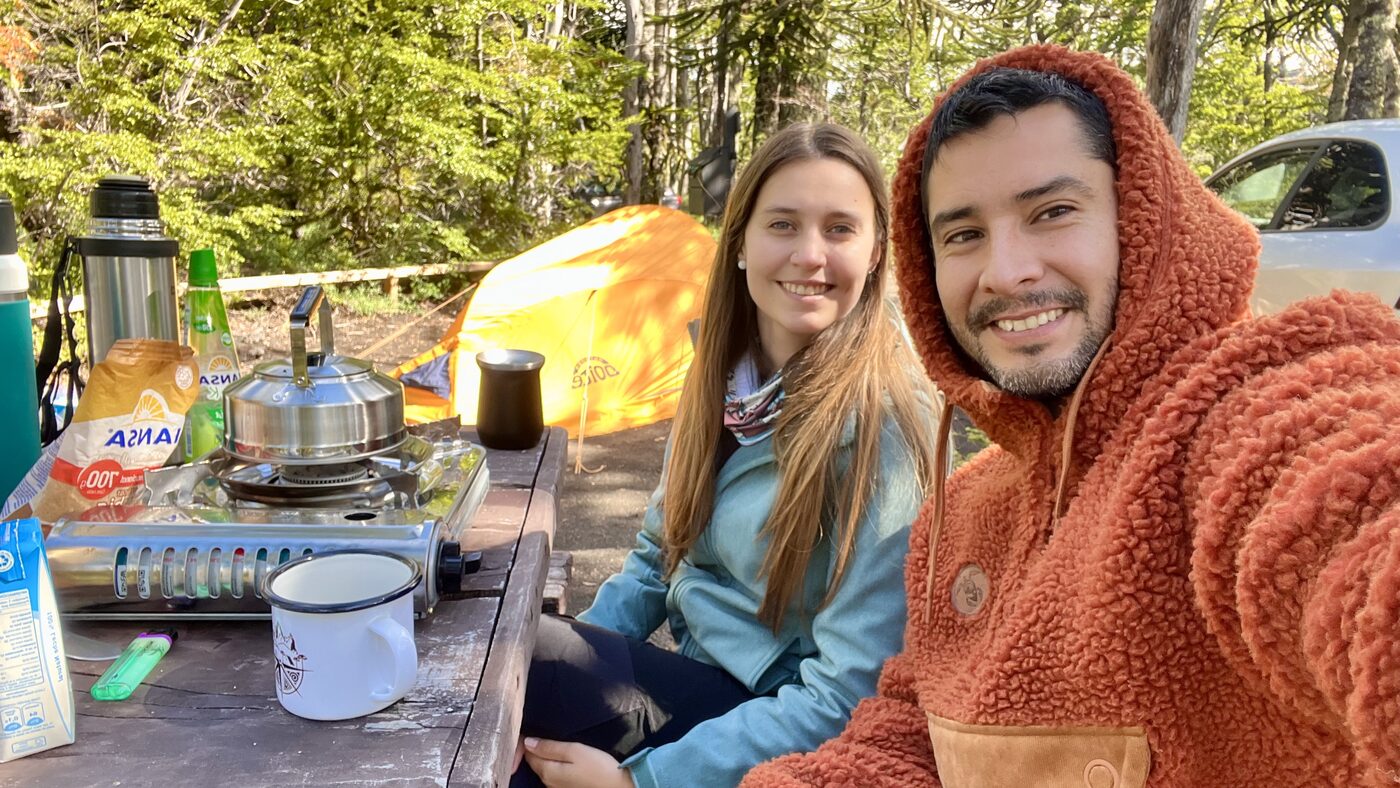 Pareja compartiendo un mate junto a la carpa en un camping del sur de Chile