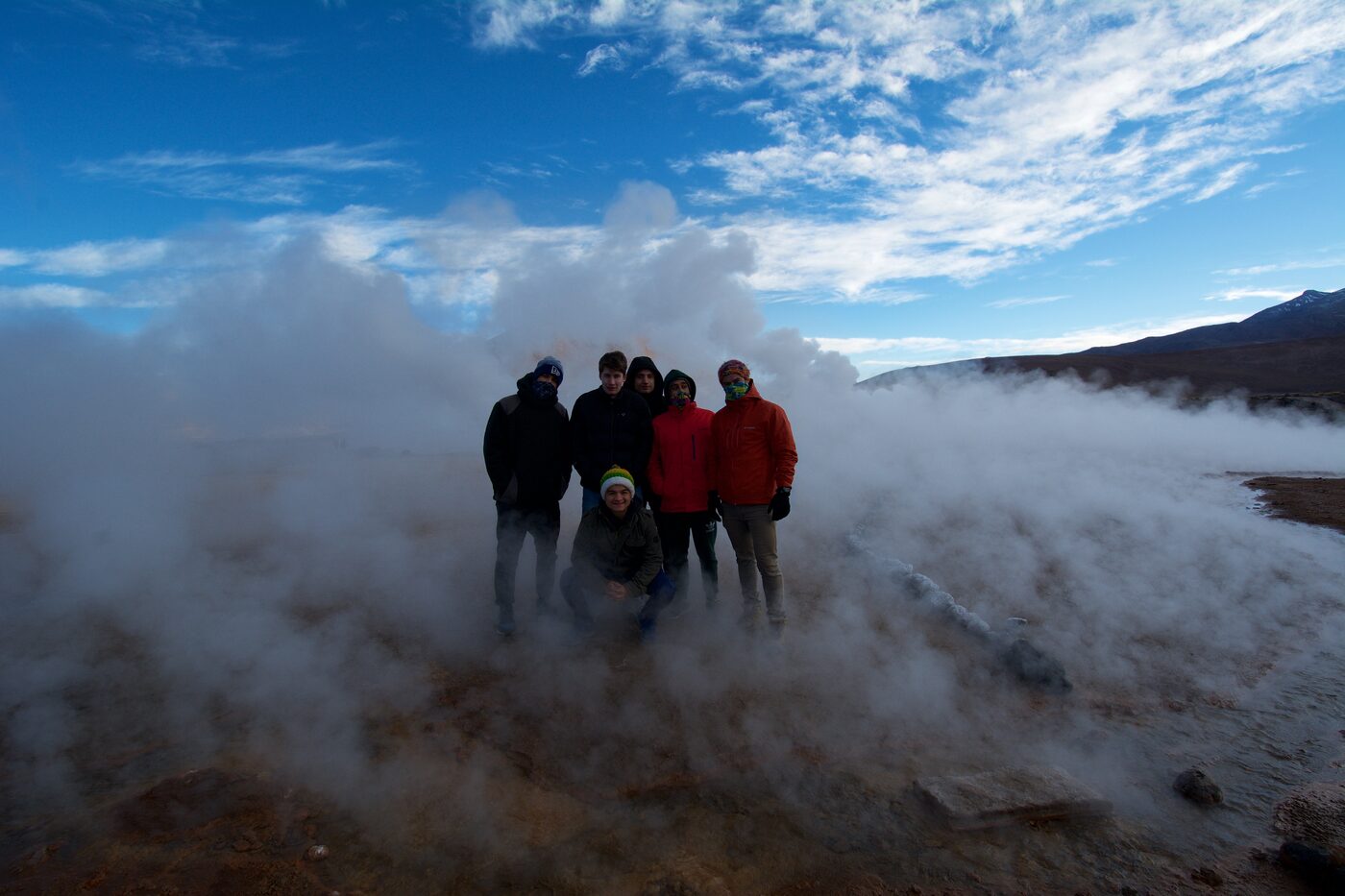 Grupo de amigos entre el vapor de los géiseres del Tatio al amanecer